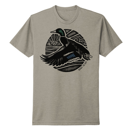 A gREY t-shirt addorned with a beeautiful male mallard duck flying in front of a monochrome sunrise.  a duck hunters dream